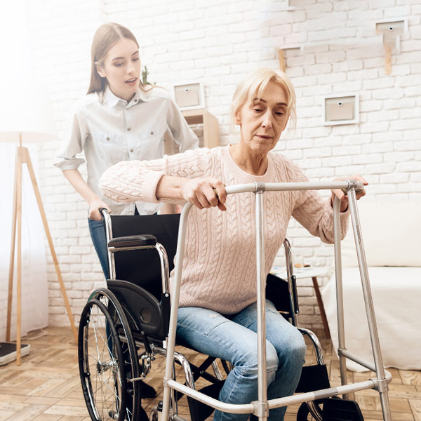 Woman in wheelchair trying to stand using a walker